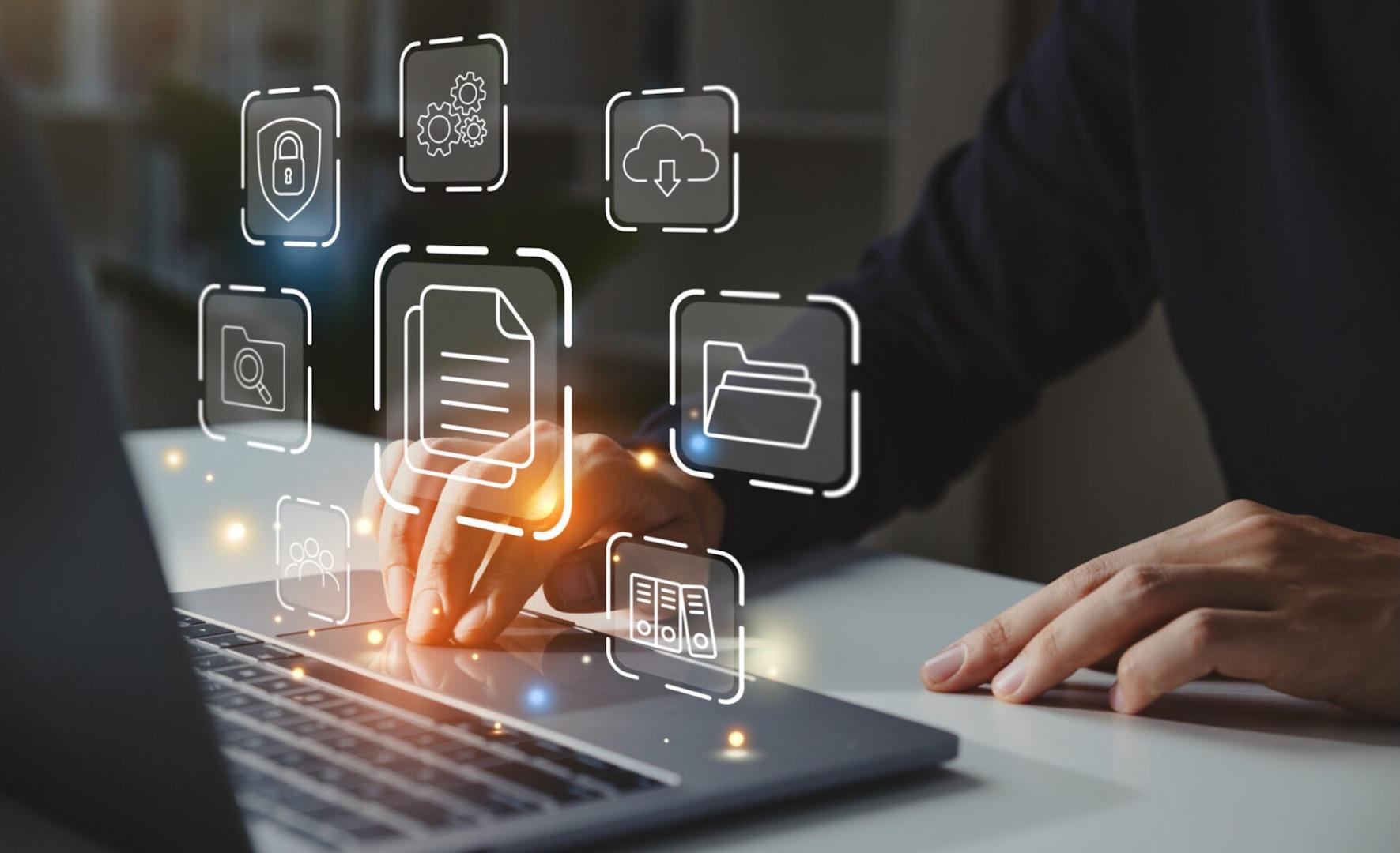 A person types on a laptop with digital icons for files, cloud storage, security, and document management appearing above the keyboard, representing digital file organization and cybersecurity.